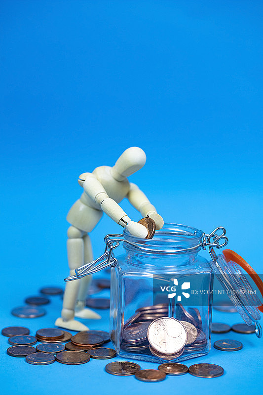 手持金钱的木制人体模型，财富的象征图片素材