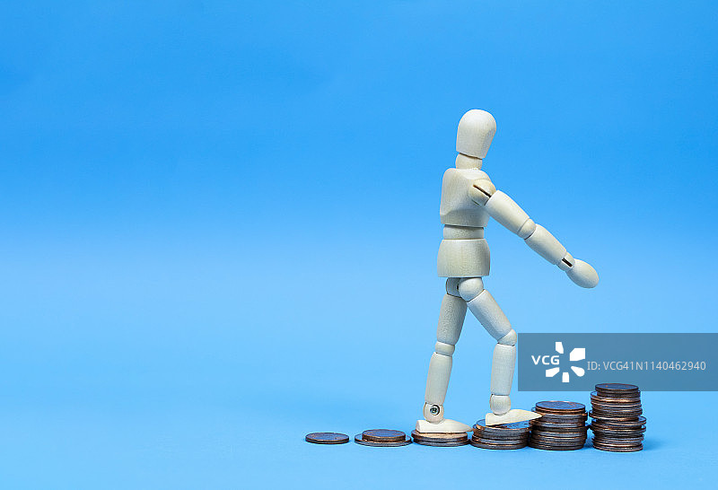 商务概念：木制人偶模型走上堆叠的金币顶部图片素材