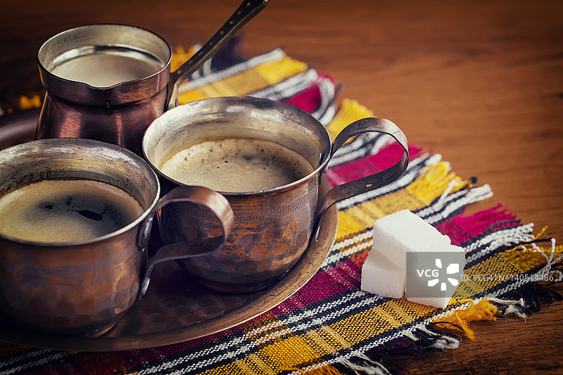 木质背景上彩色餐巾上的传统阿拉伯铜制咖啡图片素材
