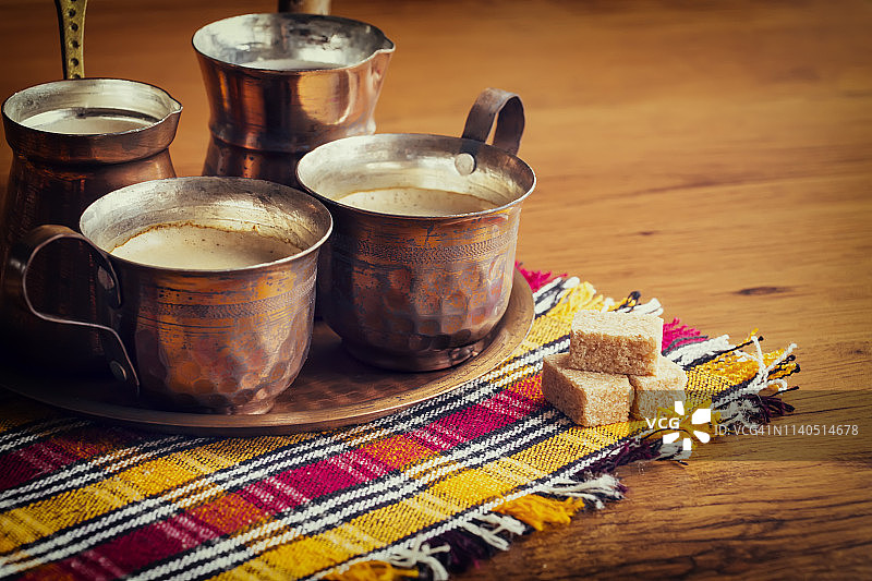 木质背景上彩色餐巾上的传统阿拉伯铜制咖啡图片素材