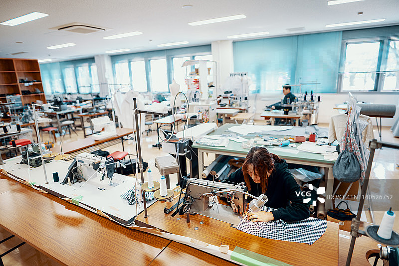 中年女人在纺织工作室的缝纫机旁工作图片素材