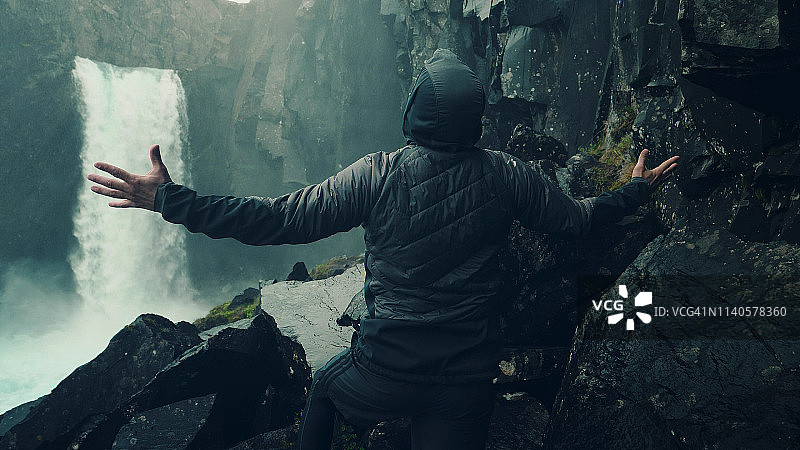 旅行者欣赏瀑布美景：张开双臂图片素材