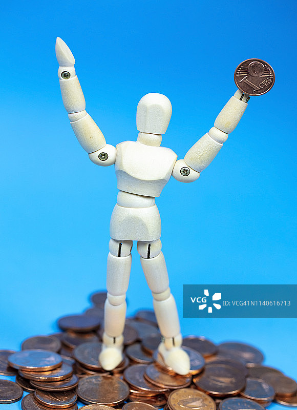 手持金钱的木制人体模型，财富的象征图片素材