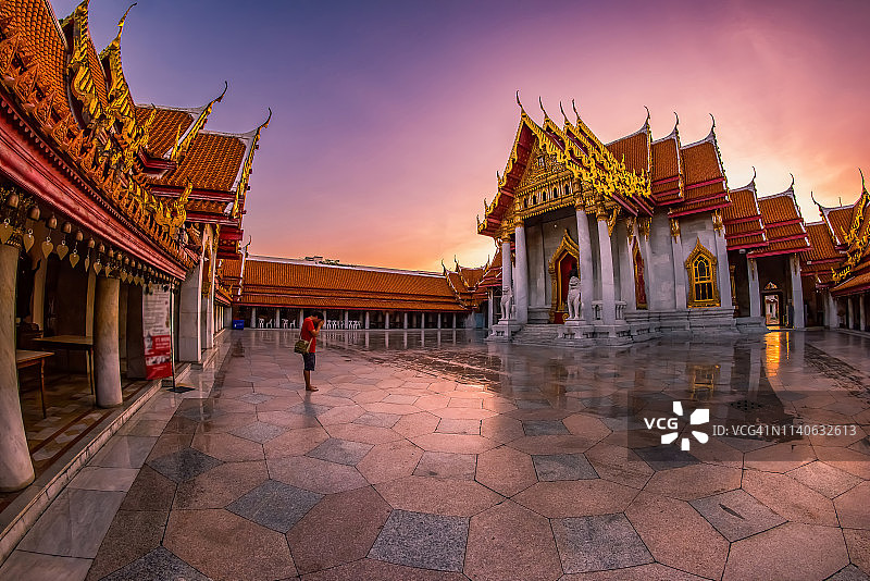 一名亚洲人站在教堂后方，黎明时分，曼谷云石寺沐浴在美丽的光芒中。图片素材