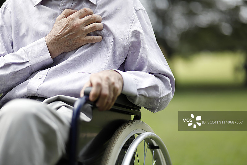 坐在轮椅上胸口疼痛的年长男人图片素材