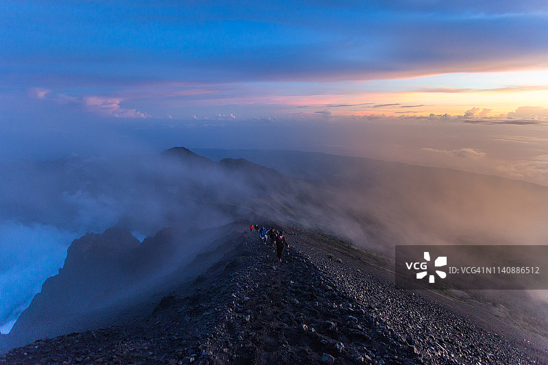 人们在日出时攀登林贾尼火山图片素材