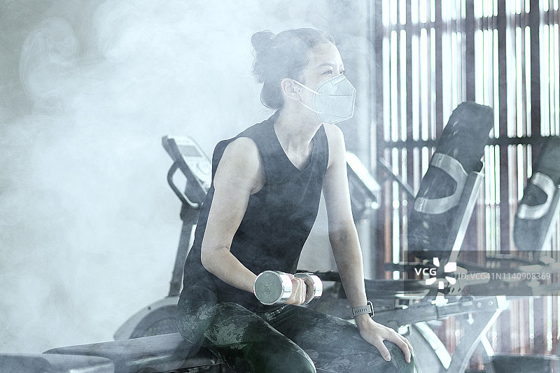 戴防雾霾口罩进行力量训练的亚洲女性图片素材