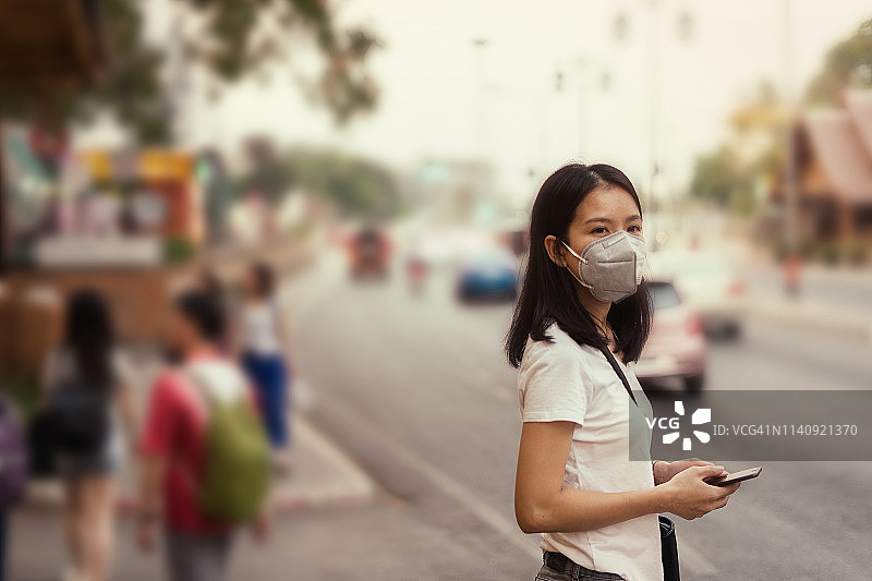 在街上戴着PM2.5口罩以防止空气污染的亚洲女孩图片素材