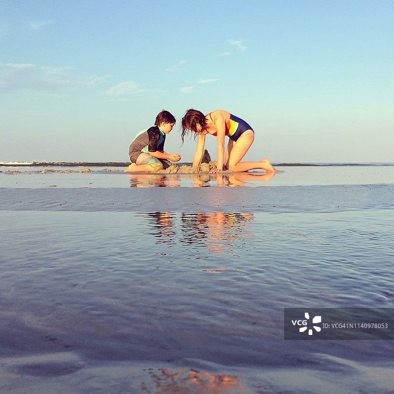 兄妹在沙滩上挖沙子图片素材