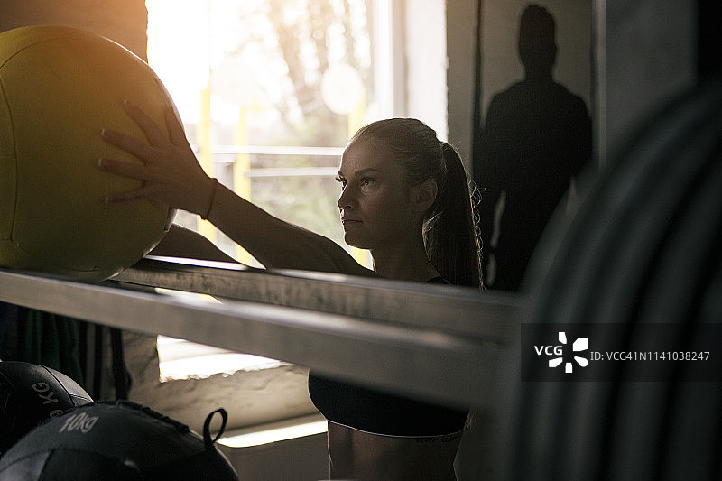 年轻女人在健身房拿起药球图片素材