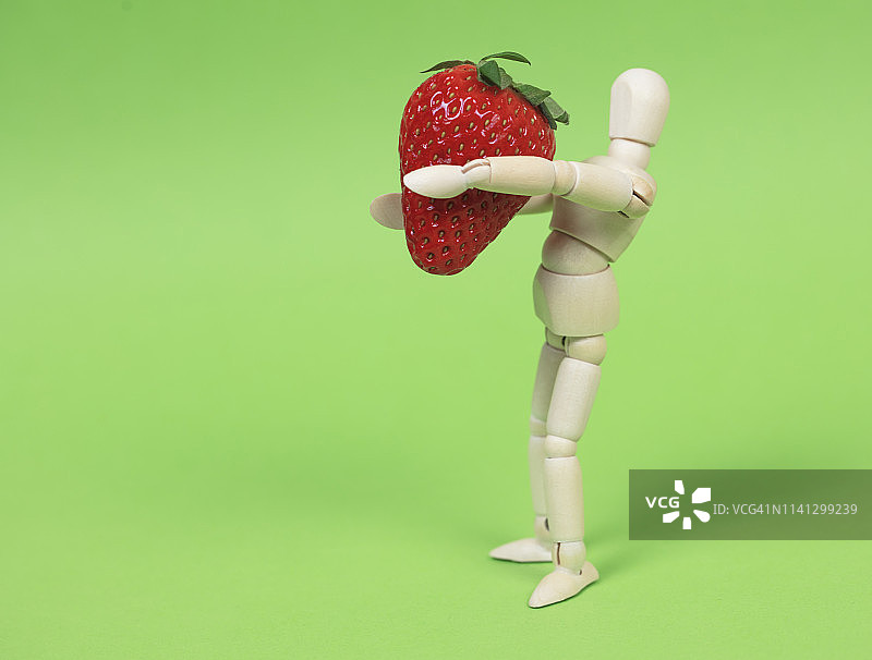 拿着草莓的木制人体模型图片素材
