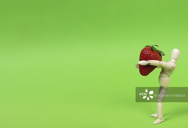 拿着草莓的木制人体模型图片素材