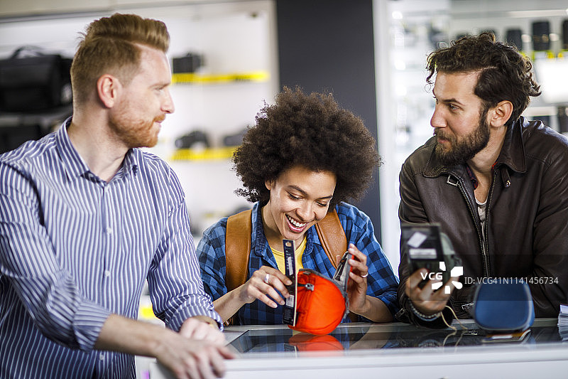 年轻夫妇在商店店员的帮助下挑选相机包图片素材