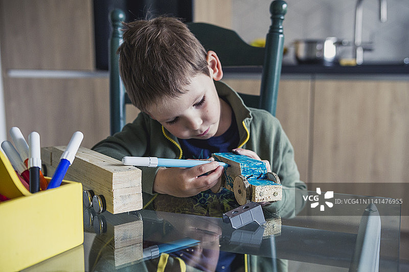 幼儿给木制汽车上色图片素材