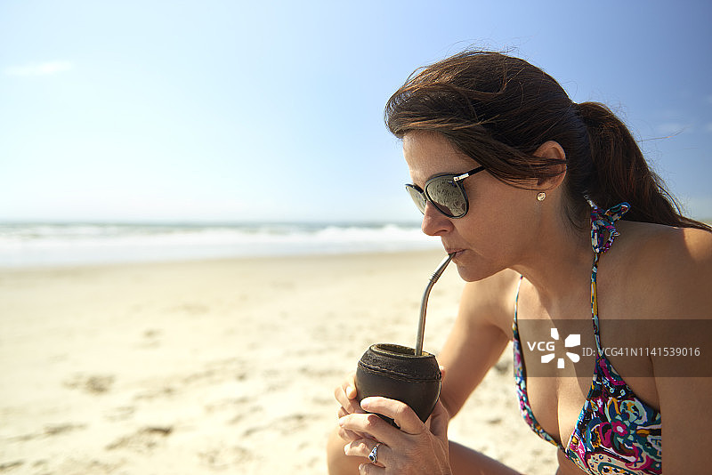 女人在沙滩喝马黛茶图片素材