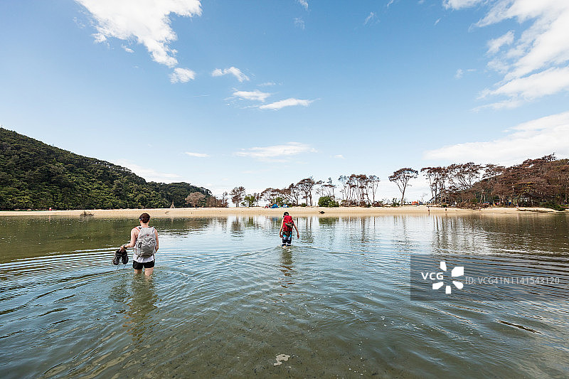 女人和男孩涉水走向宁静的海滩图片素材