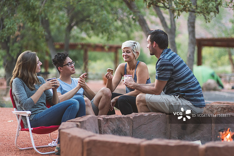 朋友们在露营地篝火旁吃烤棉花糖，进行社交活动图片素材