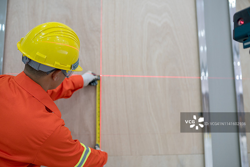 木匠使用卷尺根据激光水平仪测量数值图片素材