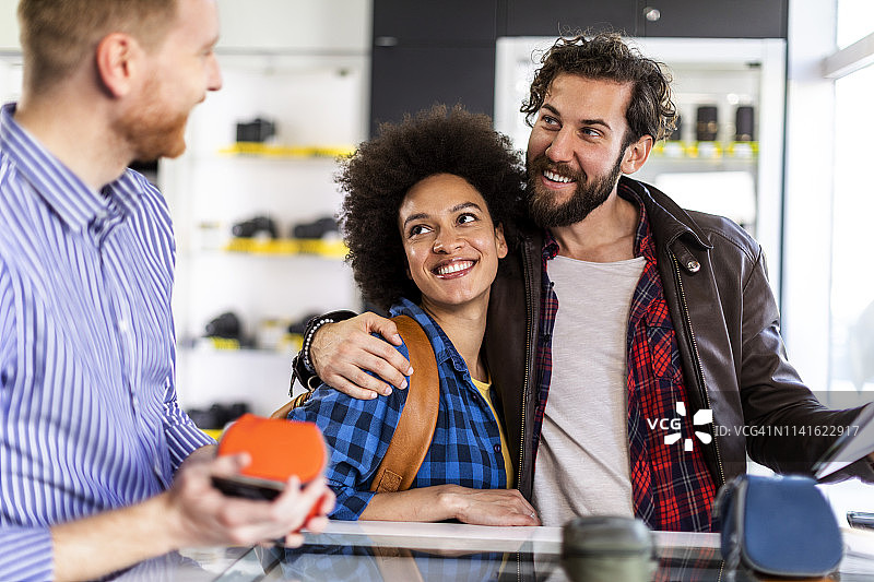 年轻情侣在相机店购买相机包图片素材
