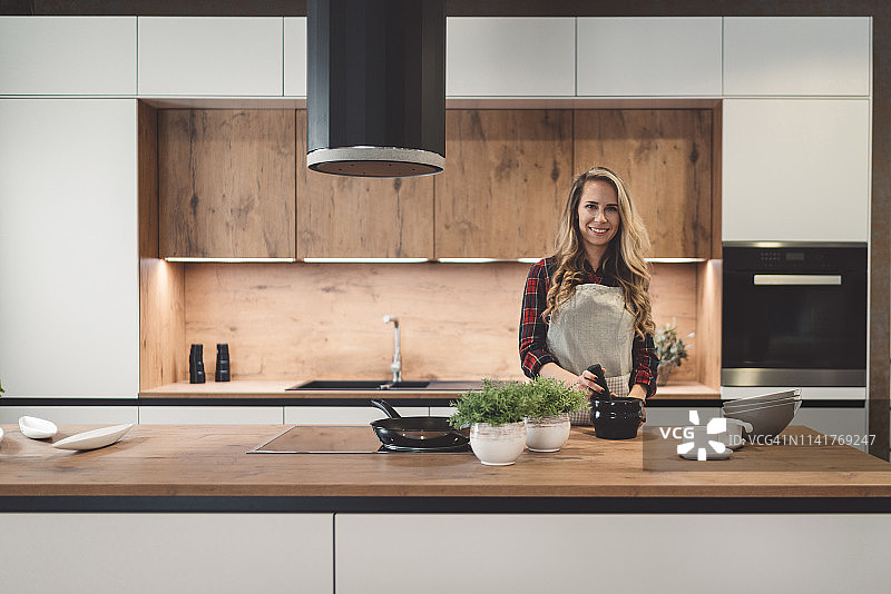 在现代厨房里拿着黑色陶器的金发女人图片素材