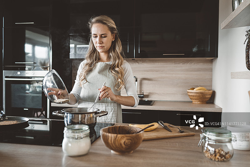 女人往平底锅里加面粉图片素材