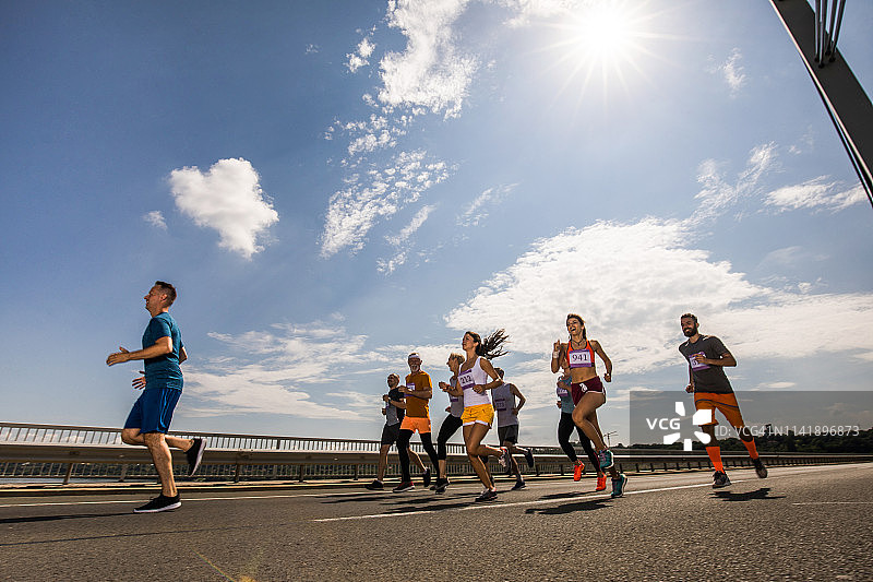 混合年龄段的运动员在桥上跑马拉松图片素材