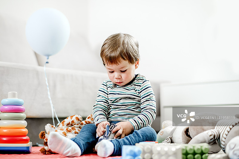 小男孩在地板上玩玩具图片素材