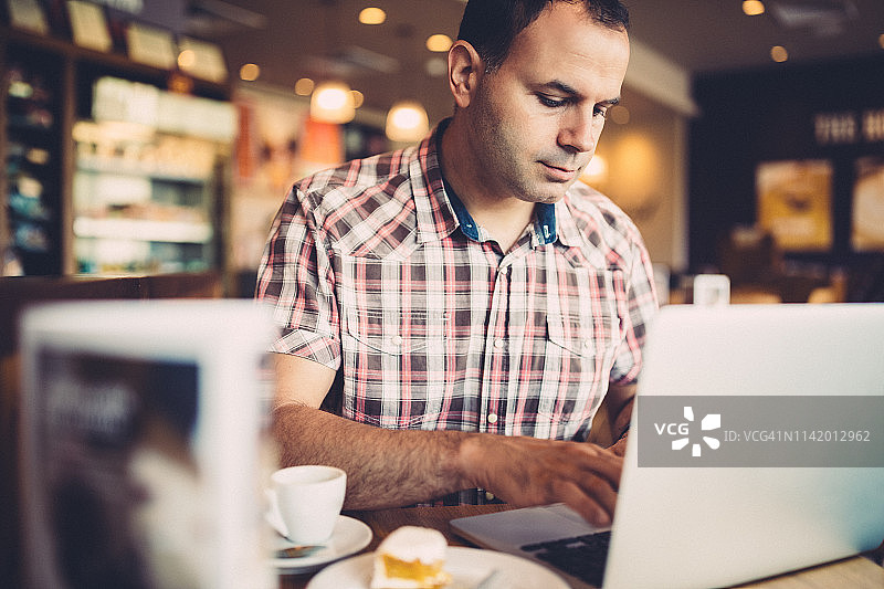 在咖啡馆用笔记本电脑工作的商人图片素材