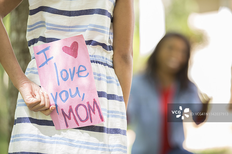 母亲节快乐。女孩给母亲送贺卡。图片素材