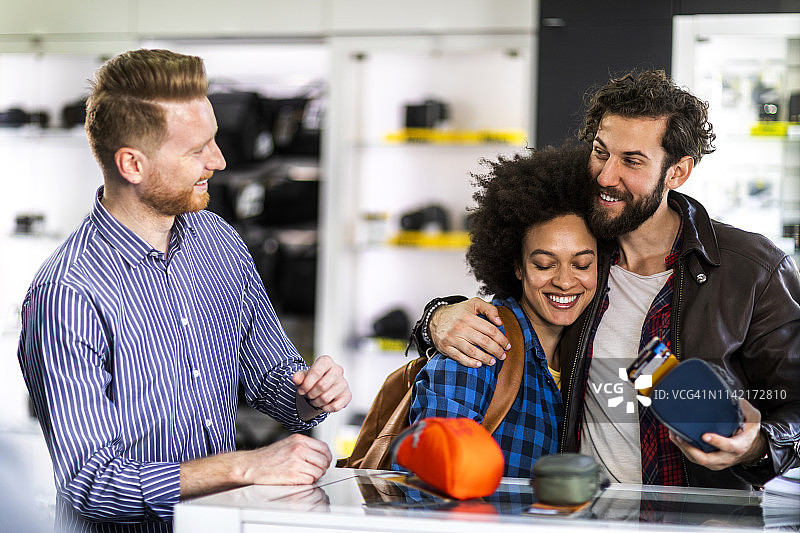 年轻情侣在相机店购买相机包图片素材
