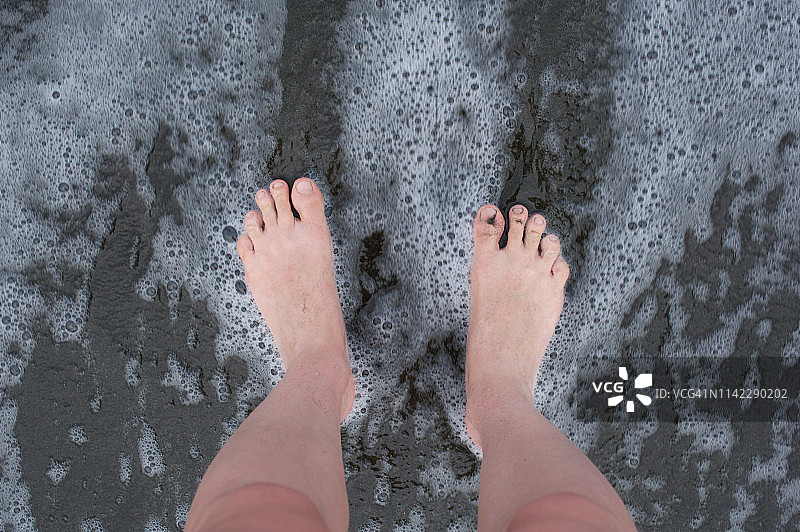 站在哥斯达黎加的黑沙滩上，光着脚图片素材