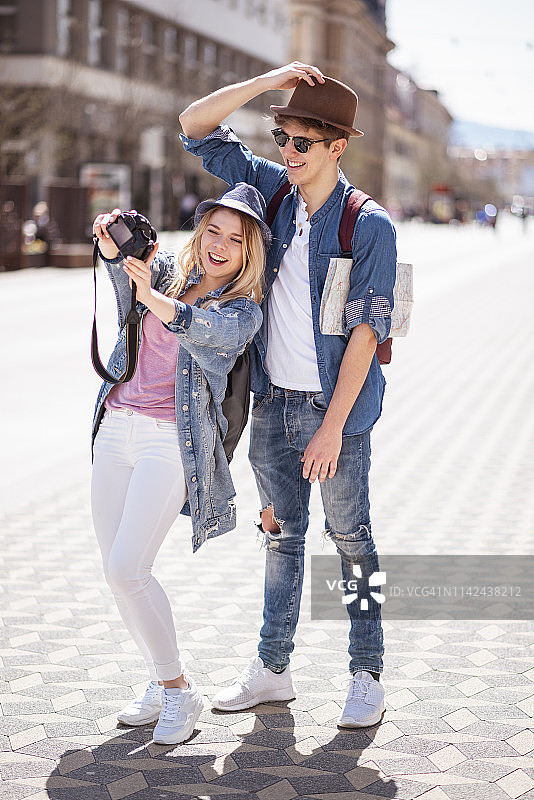 快乐的年轻夫妇在城市街道上自拍图片素材