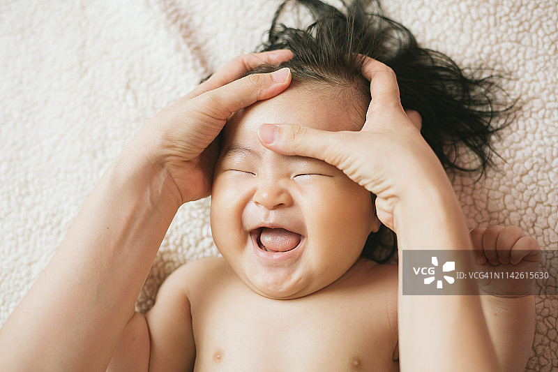 母亲为女婴（6-11个月）擦润肤露图片素材