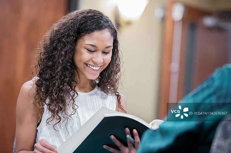 年轻女子在大学图书馆或公共休息室学习课本图片素材