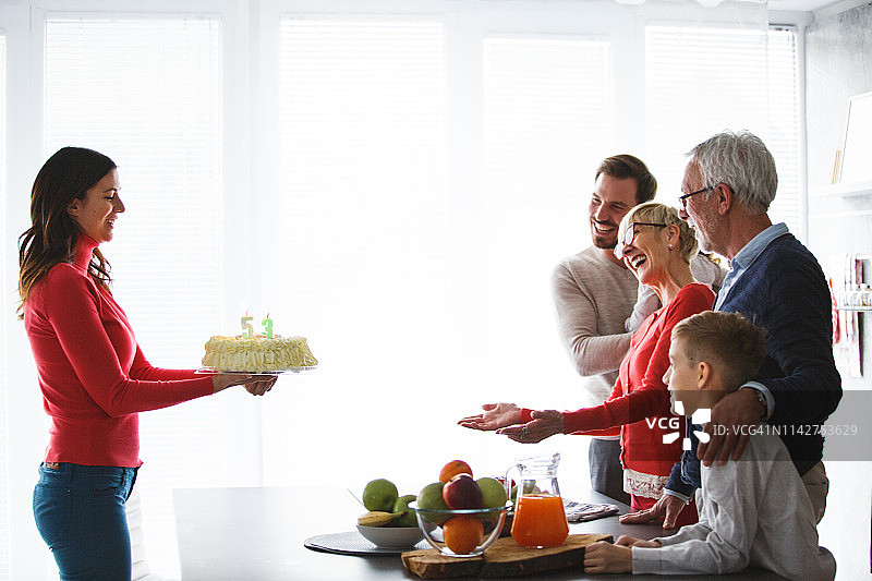 家人用生日蛋糕给中年妇女一个惊喜图片素材