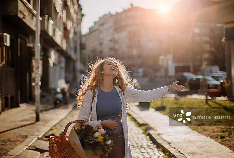 手捧鲜花走在城市街道上的年轻人图片素材