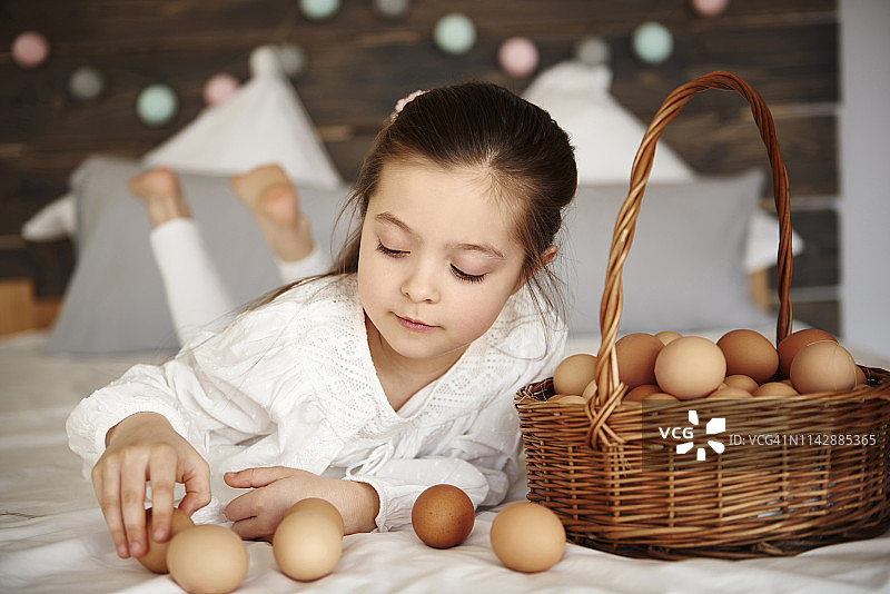 女孩在床上玩鸡蛋，波兰德比察图片素材