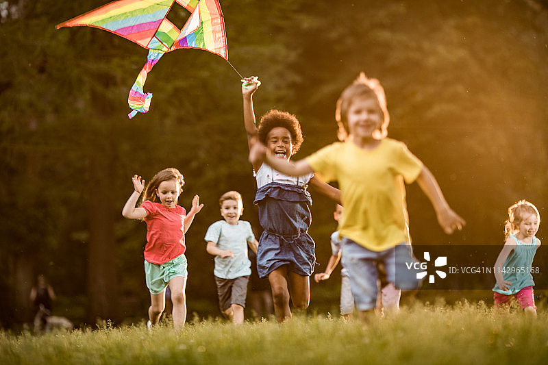 快乐的孩子们在春天的公园里放风筝图片素材