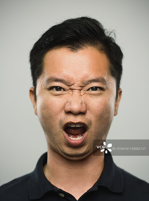 带着愤怒表情的真实中国男子肖像图片素材