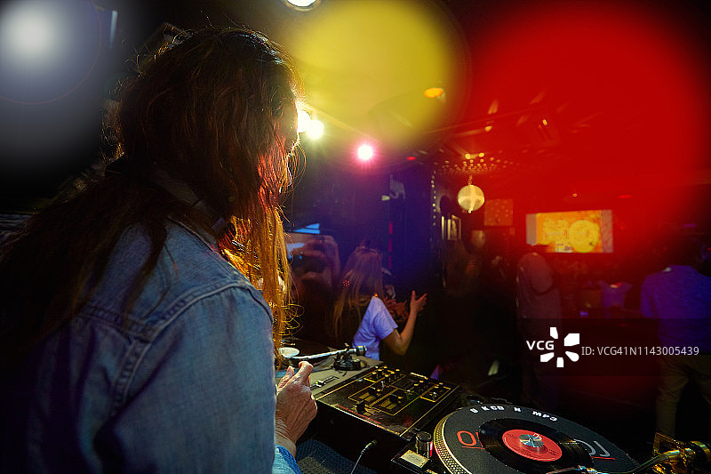 DJ在时髦的夜晚用转盘混合音乐的背面镜头图片素材