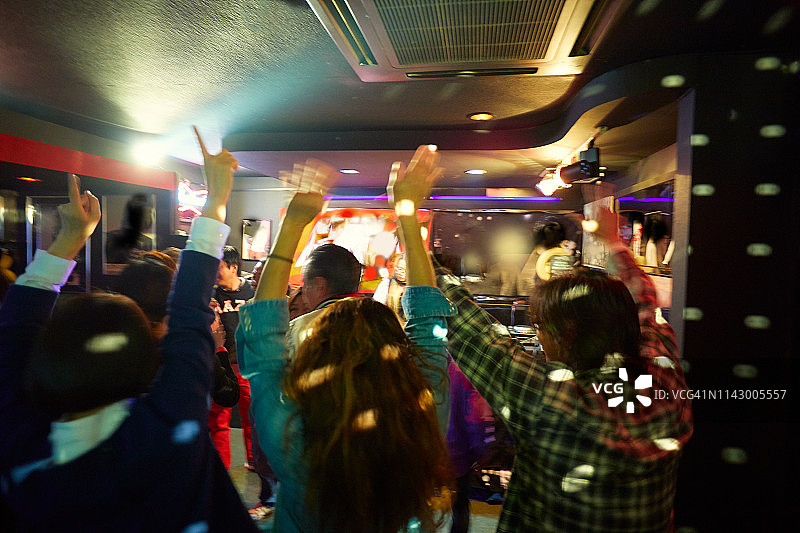 在时髦的夜晚派对上挥舞手臂的人群图片素材