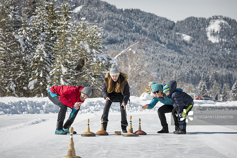 在魏森湖上玩冰壶的家庭 - 冬季旅游图片素材