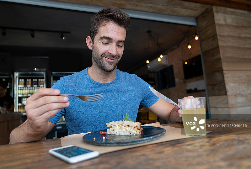 巴西男人在咖啡馆吃三明治图片素材