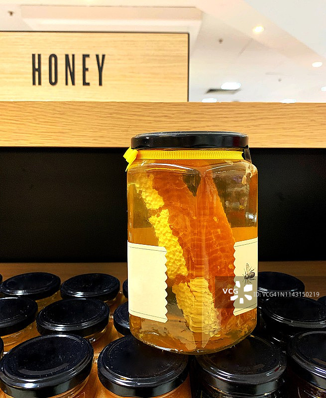 商店里堆叠的蜂蜜罐，木制蜂蜜标志，有机蜂蜜和蜂窝特写图片素材