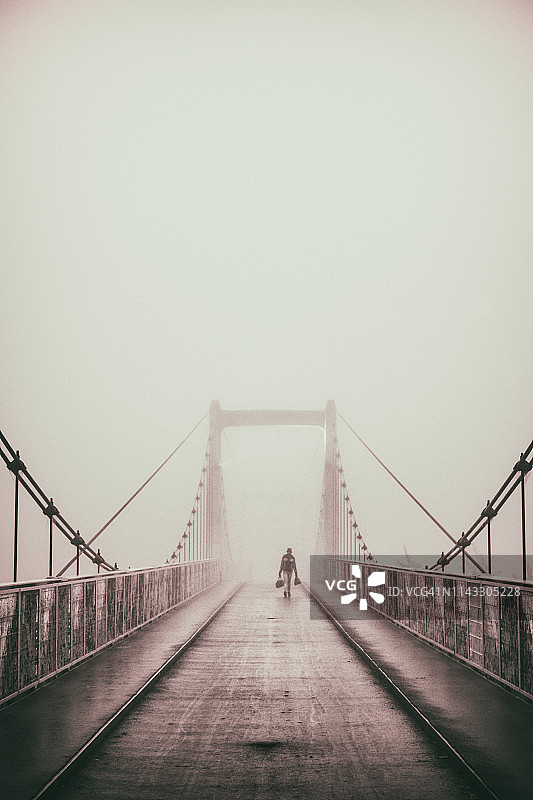 雾中桥：行人肩扛两袋图片素材