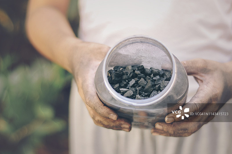 手从罐子里倒出木炭碎图片素材