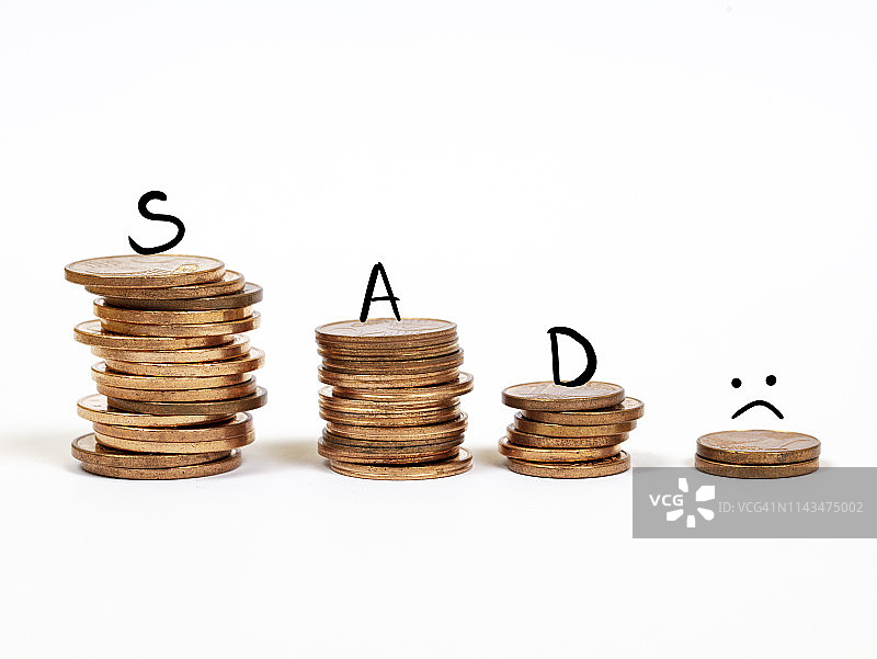 堆叠的钱币，顶部带有悲伤的表情图片素材