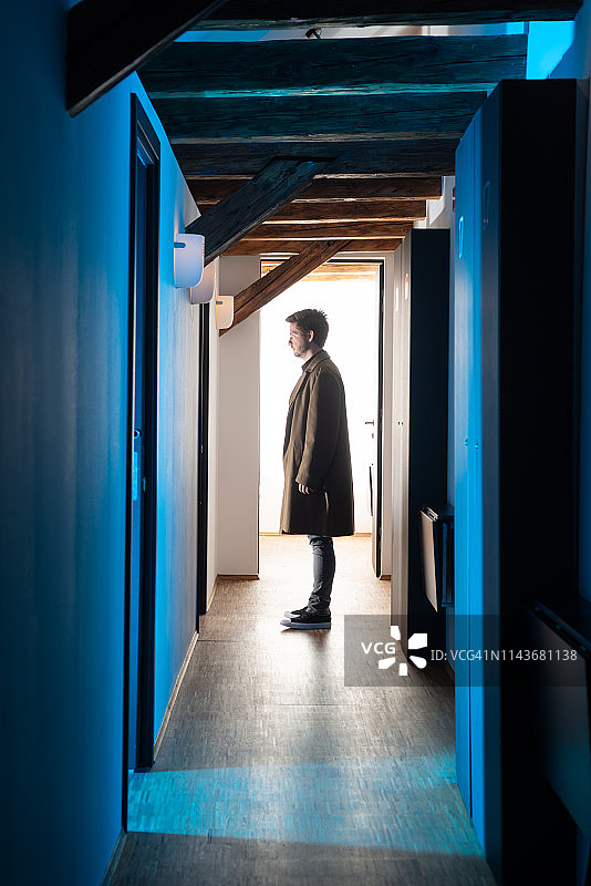 酒店走廊里站在房间前的神秘男子图片素材