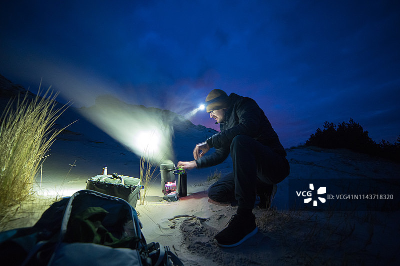 夜晚的海滩营地。男人准备饭菜图片素材