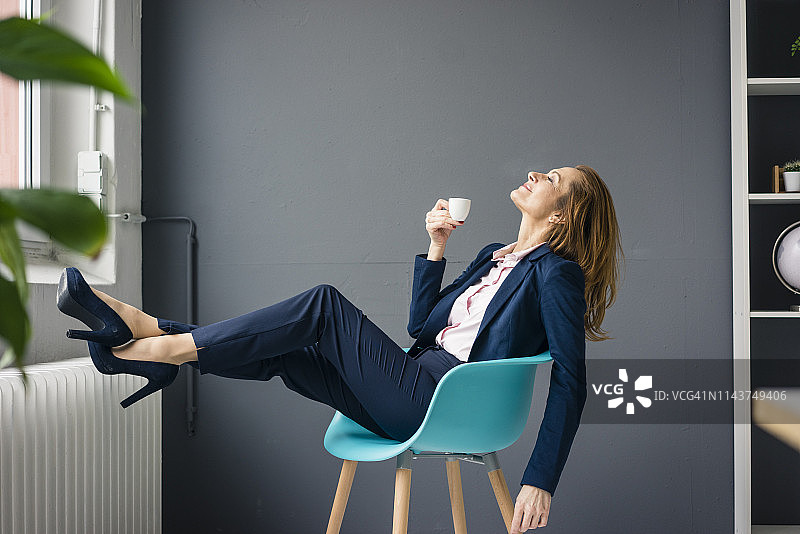 女商人休息，坐在窗边的椅子上喝咖啡图片素材
